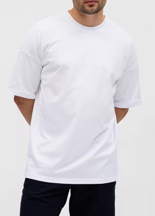 Man wearing a plain white t-shirt and dark shorts on a light gray background